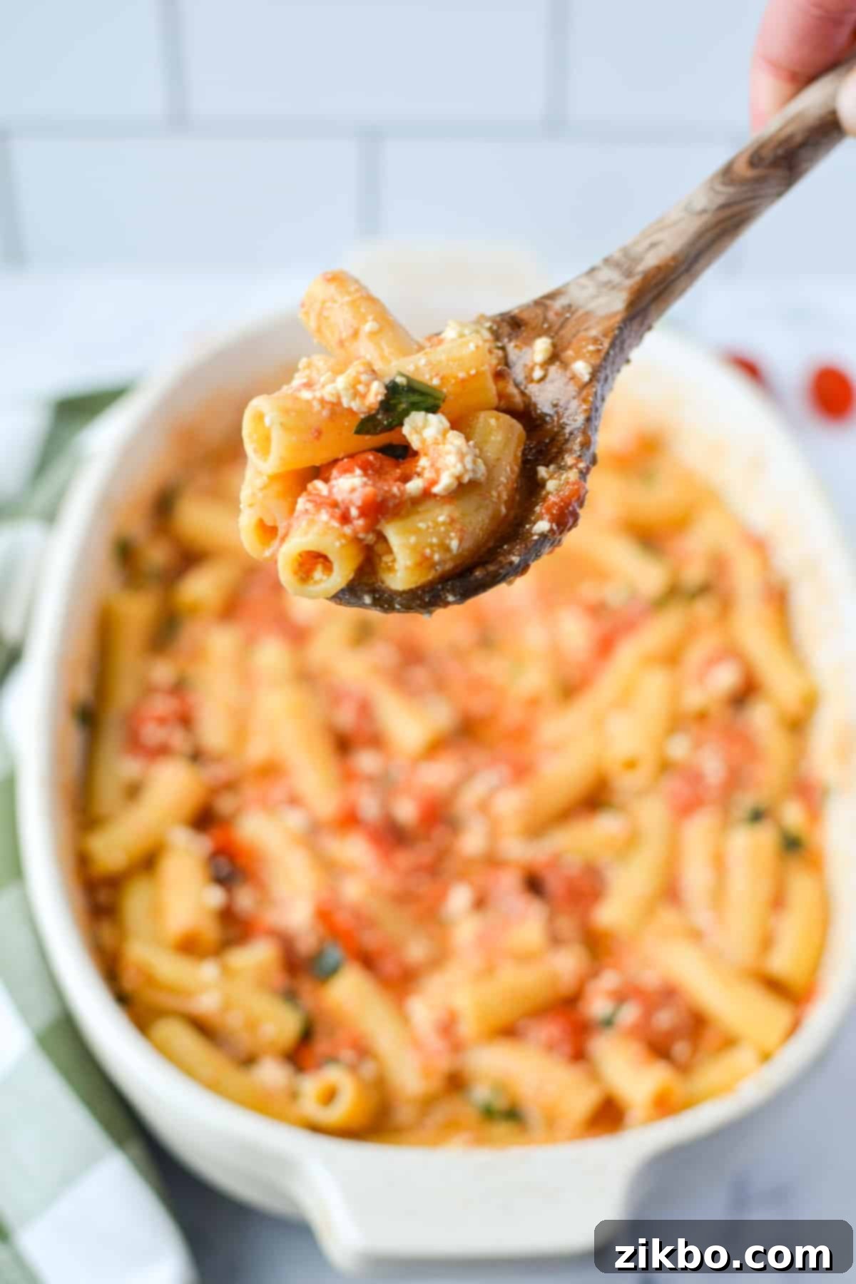 A baking dish of pasta, with a spoon taking a portion.