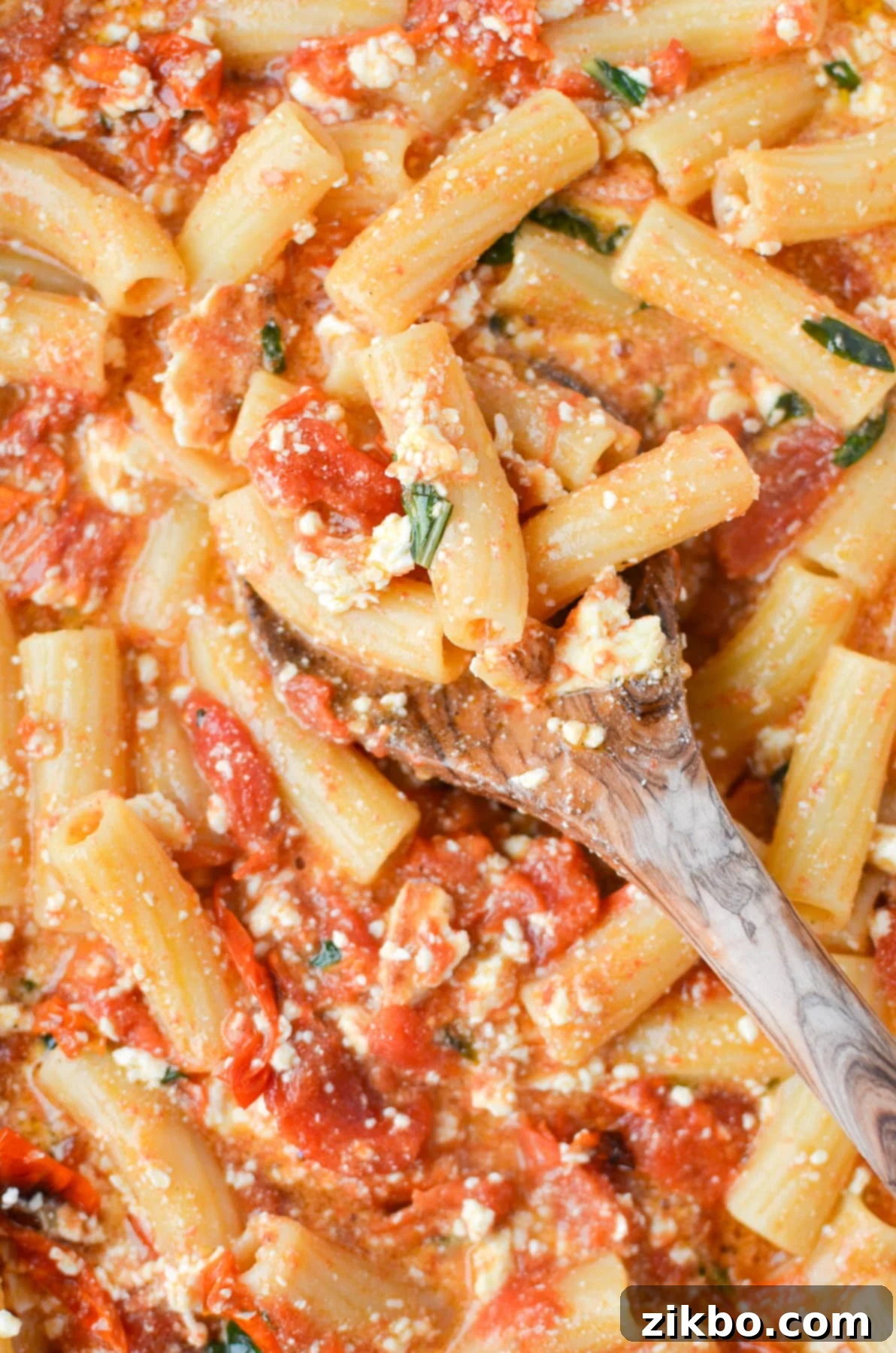 Spooning pasta with a wooden spoon.
