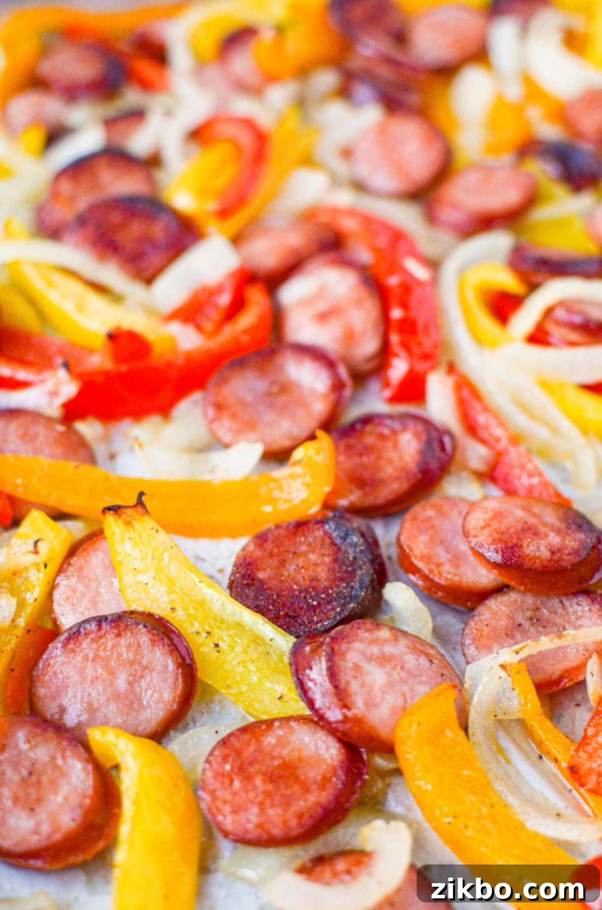 A close-up view of the perfectly cooked smoked sausage and peppers on a sheet pan, showcasing the rich colors and textures.