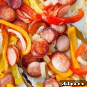 Tongs taking a portion of sausage rounds with peppers and onions.