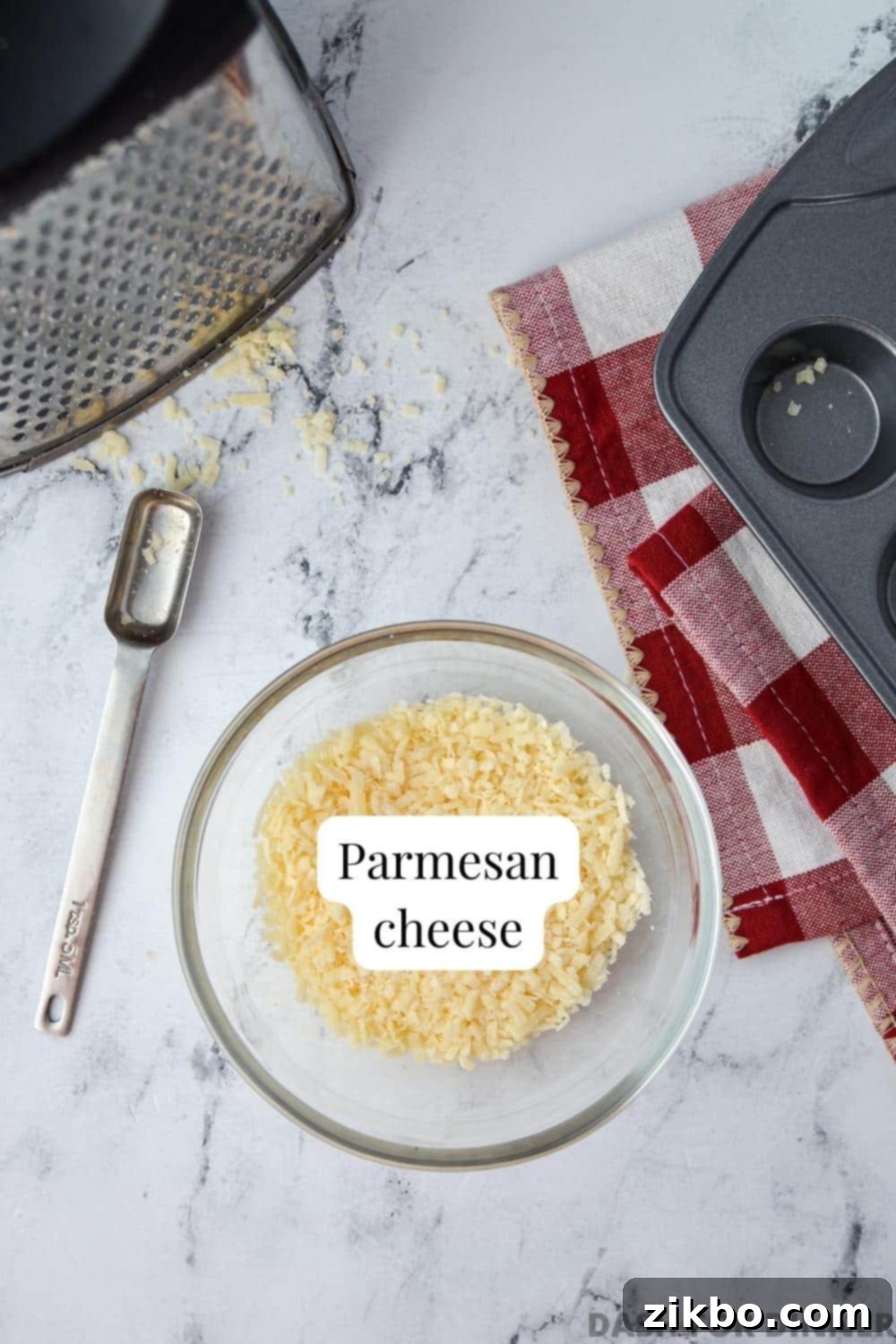 Savory Parmesan Snaps 3 A bowl of parmesan cheese, with a box grater and mini muffin pan to the side.