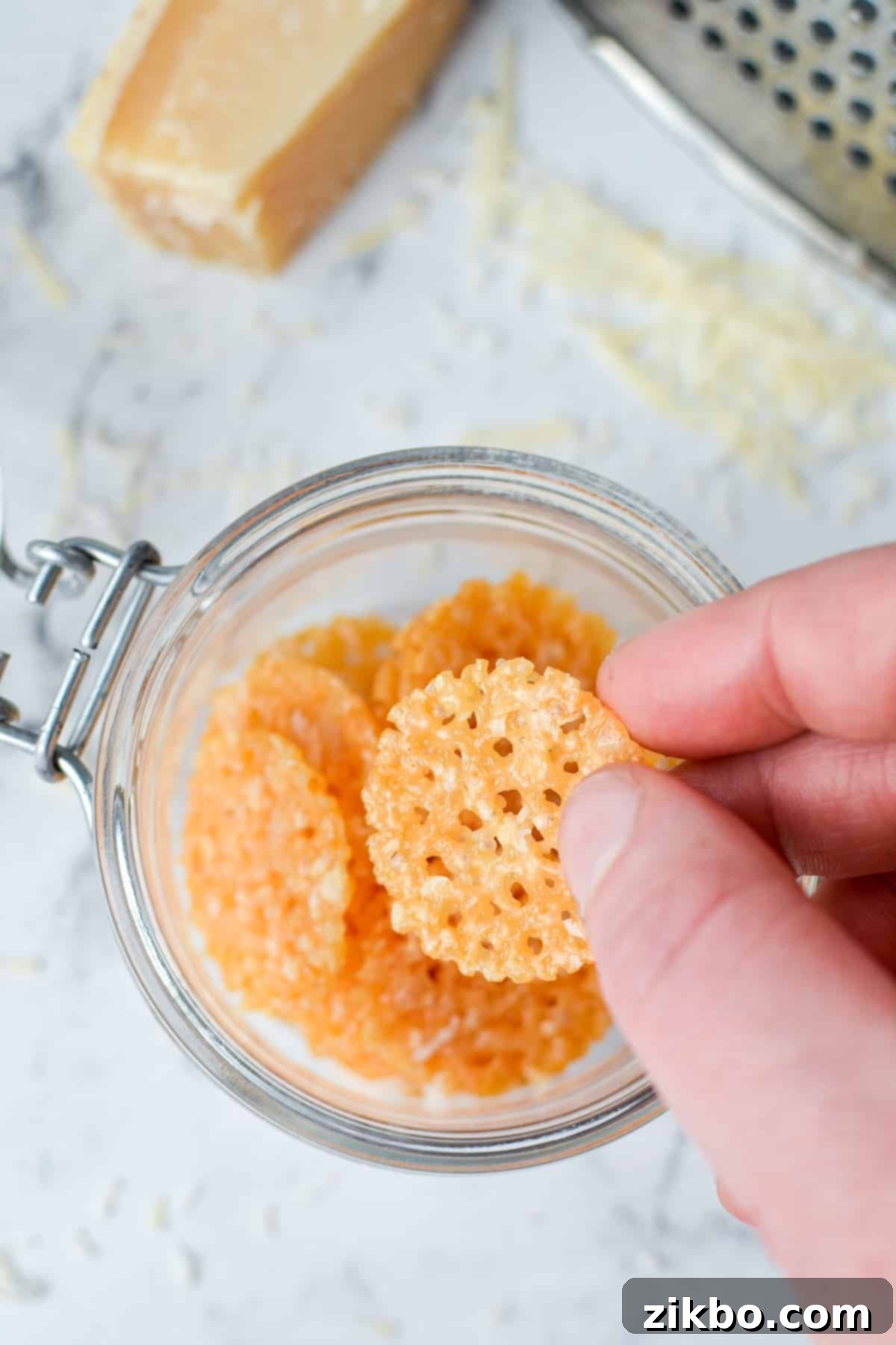 Savory Parmesan Snaps 10 A hand taking a cheese chip from a jar.