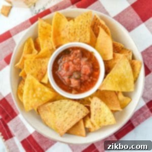 A bowl of tortilla chips with salsa in the middle.