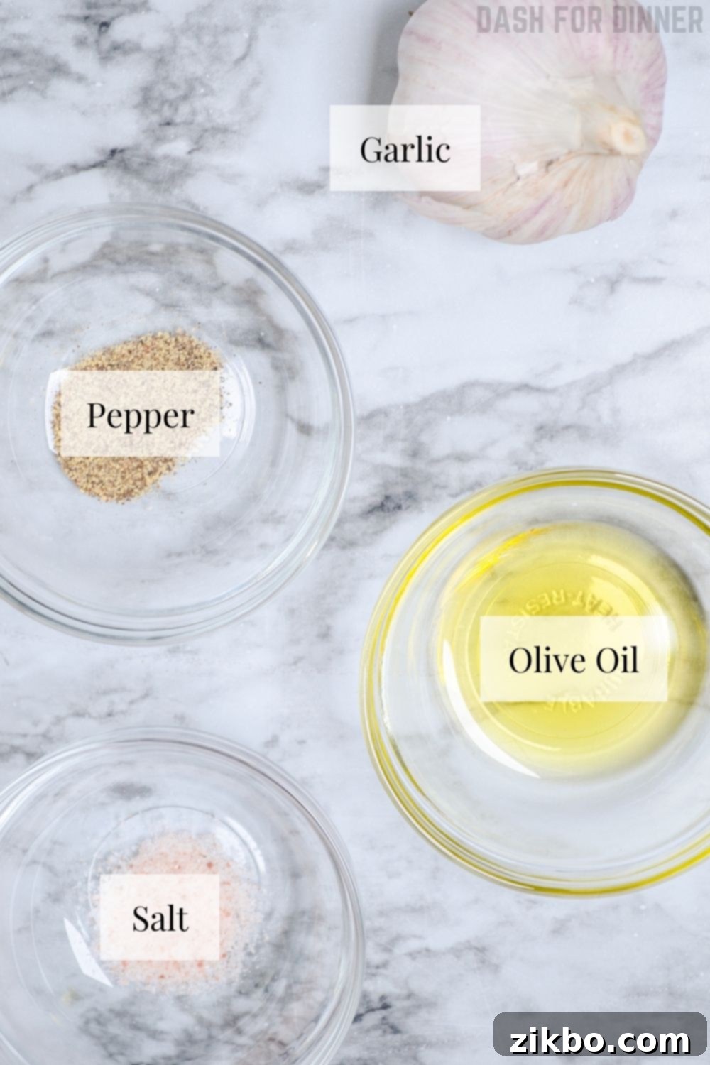 Ingredients laid out for making air fryer roasted garlic: a fresh garlic bulb, olive oil, salt, and pepper.