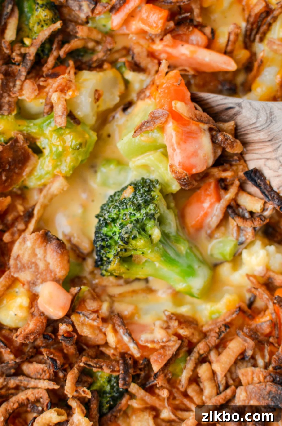 A golden-brown cheesy vegetable casserole with broccoli florets visible, topped with crispy fried onions, ready to be served.
