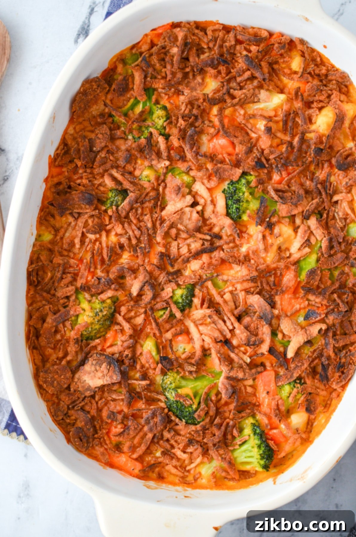 A finished cheesy vegetable casserole with a golden-brown, crispy fried onion topping, fresh out of the oven.