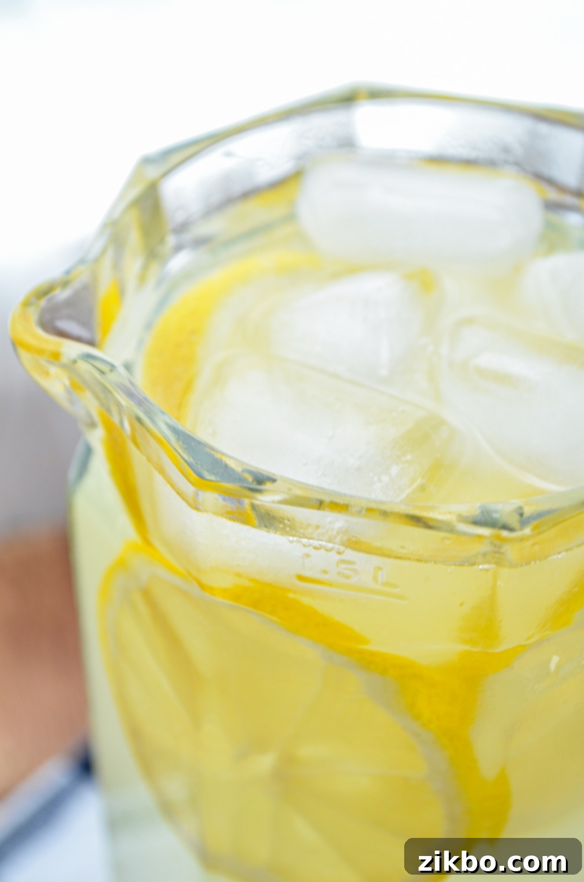 A large glass pitcher filled with freshly made Instant Pot lemonade, garnished with lemon slices, ready for chilling.