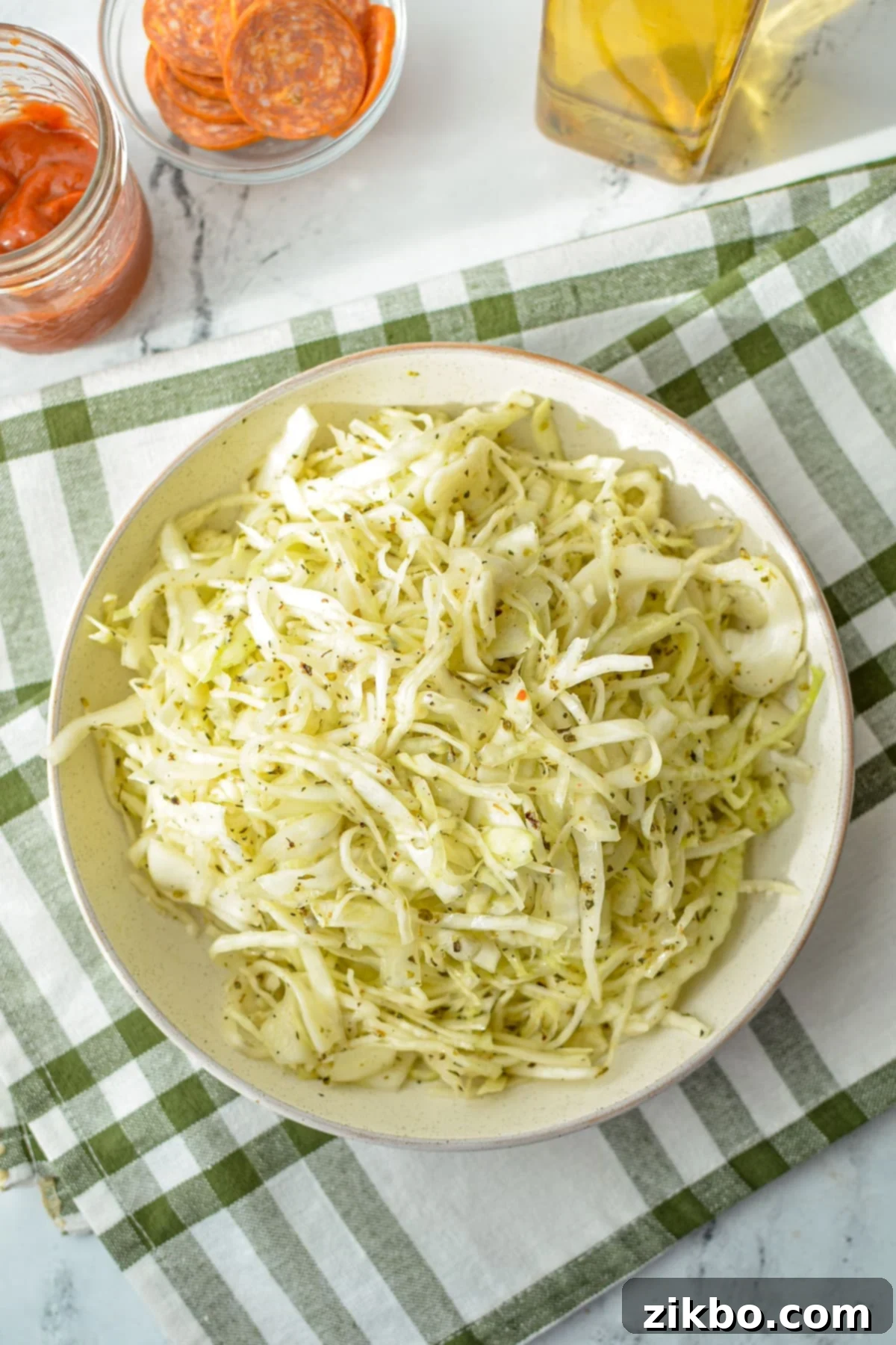 A bowl of shredded cabbage topped with an oil and vinegar dressing.