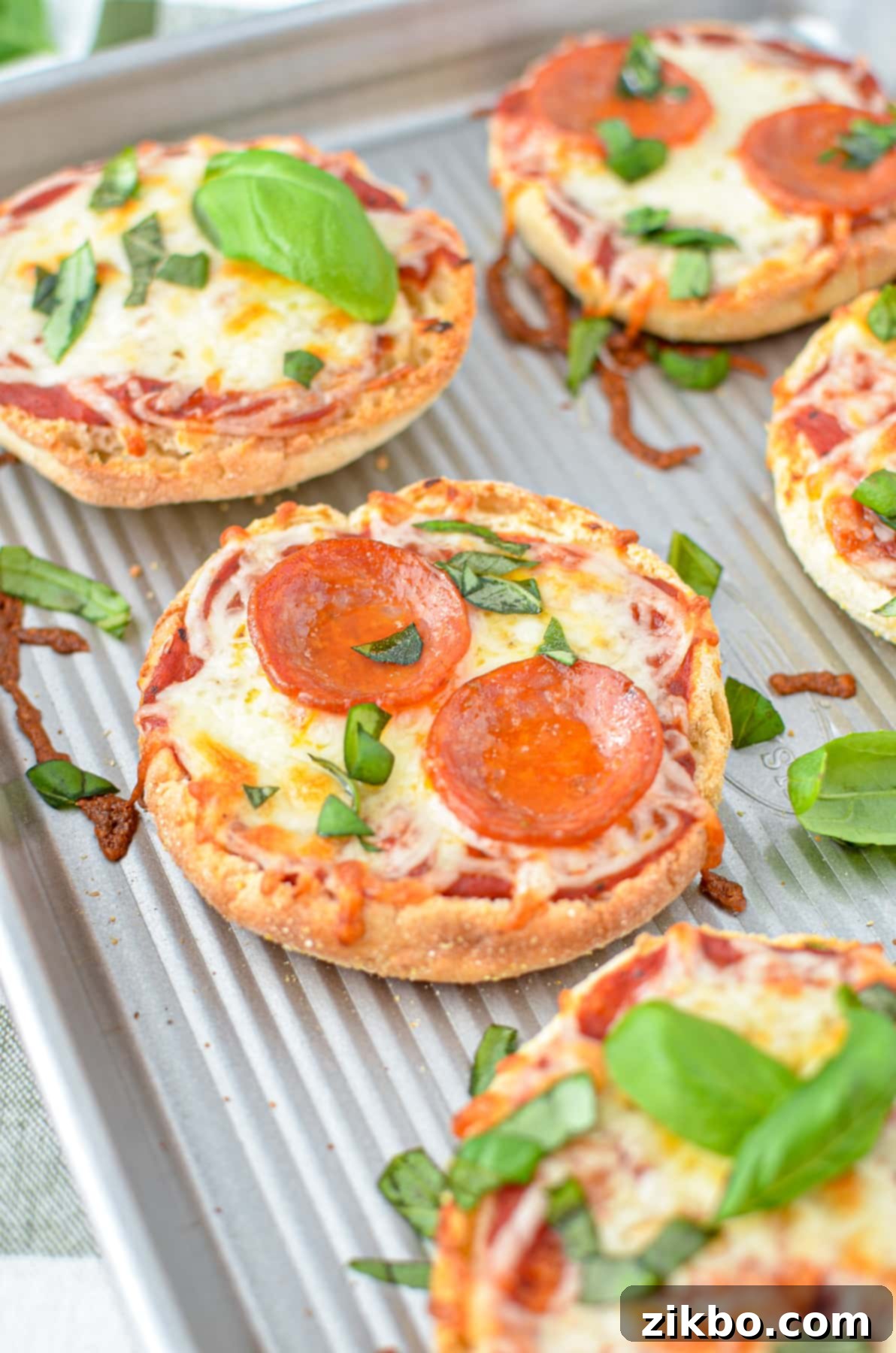 Easy English Muffin Pizzas 10 A close up of a mini pizza topped with pepperoni and basil.