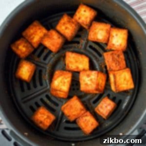 Quick Air Fryer Paneer 8 An air fryer basket with paneer cubes in it.