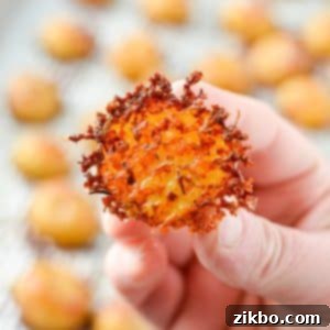 Crispy Parmesan Potatoes 10 A hand holding a halved baby potato encrusted with parmesan cheese, ready to be served.