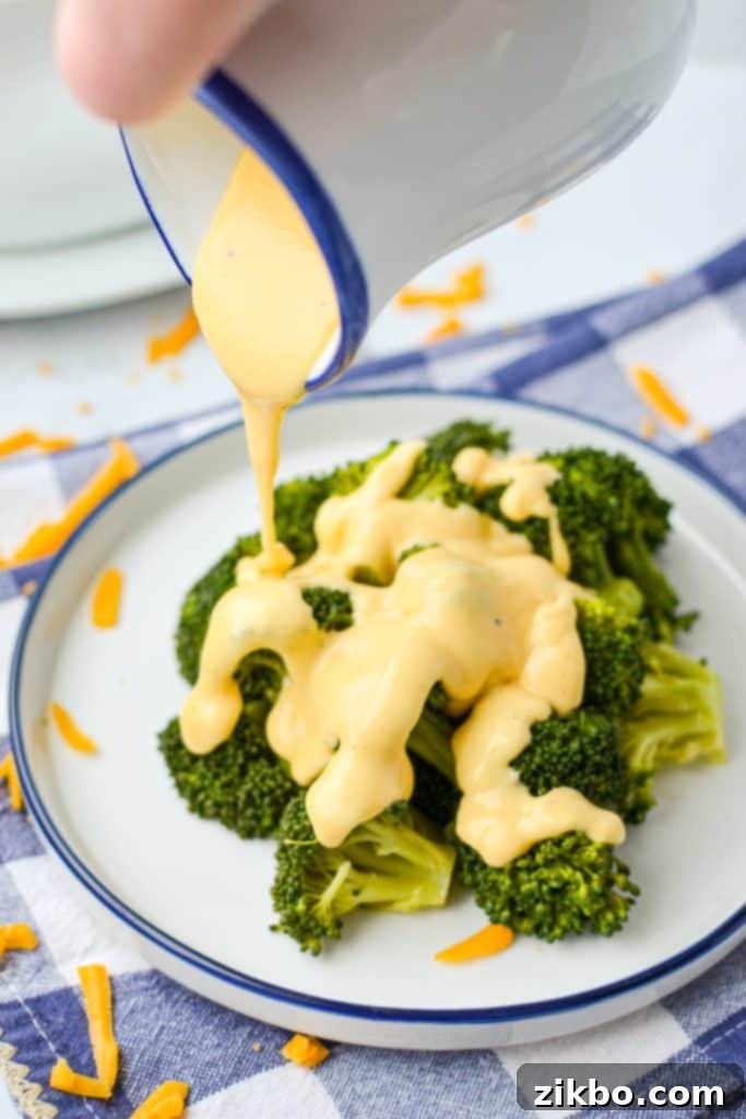 Drizzling cheese sauce on top of broccoli.