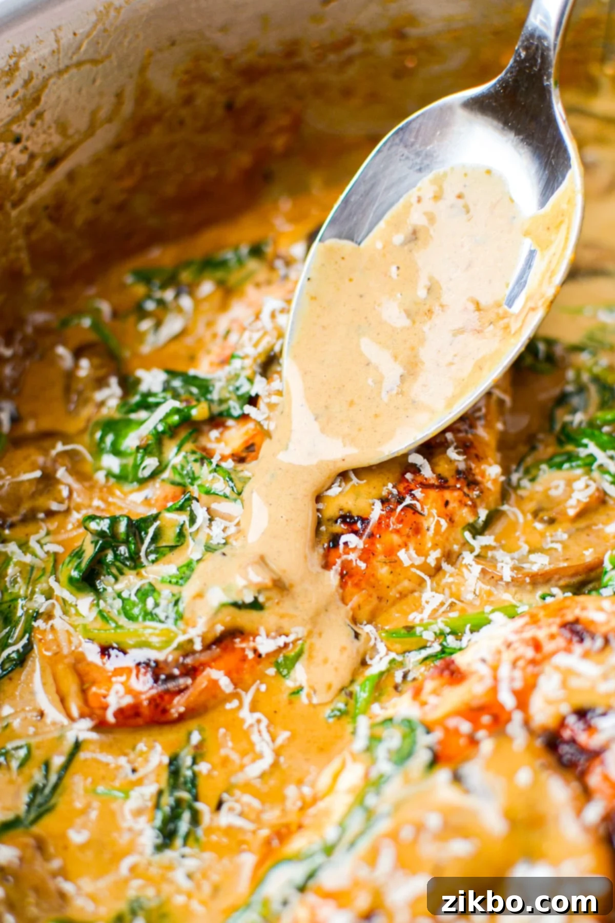 Spooning creamy sauce over a chicken breast.