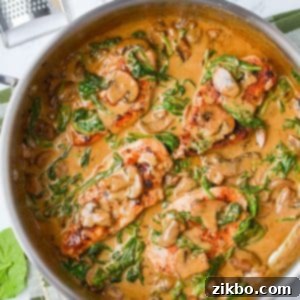 A skillet with chicken covered in a creamy sauce.