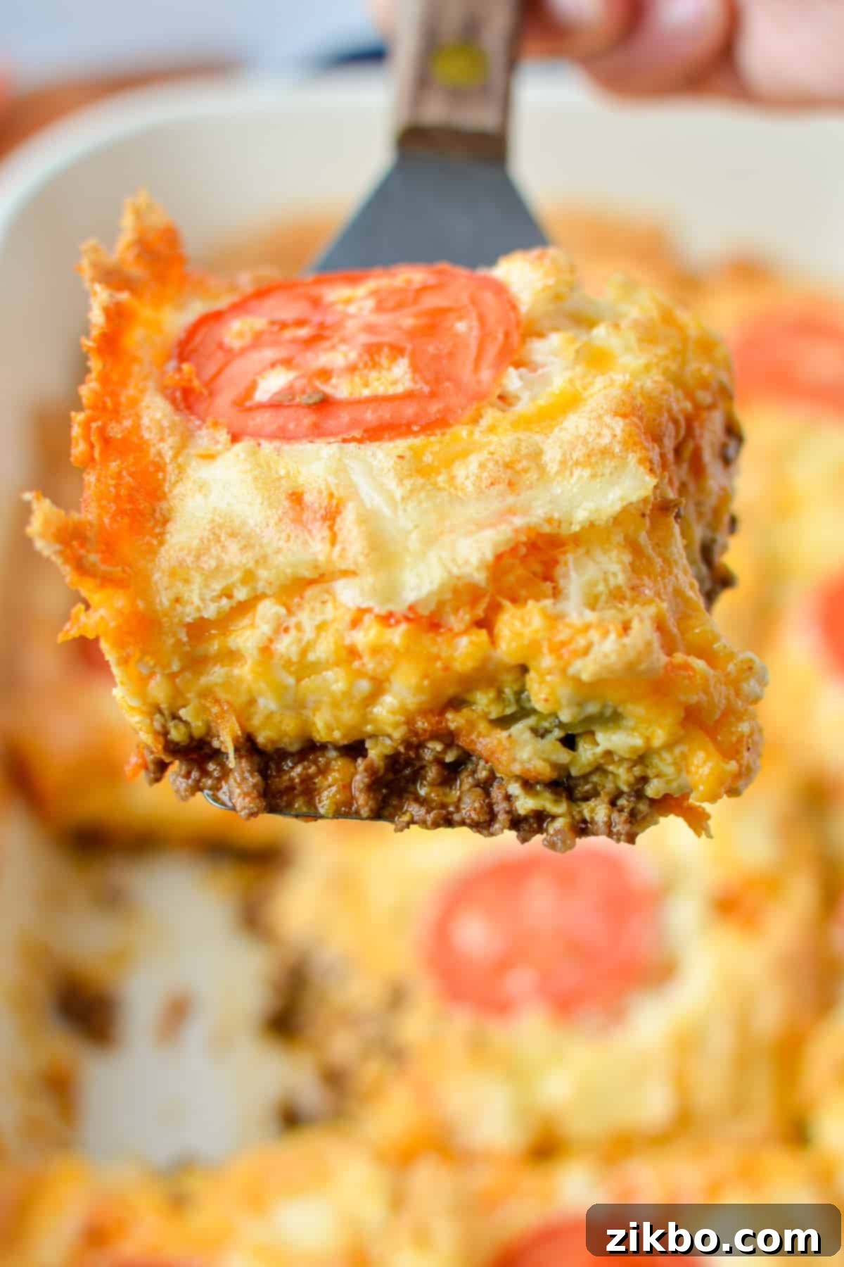 Lifting a slice of taco casserole out of a baking dish.