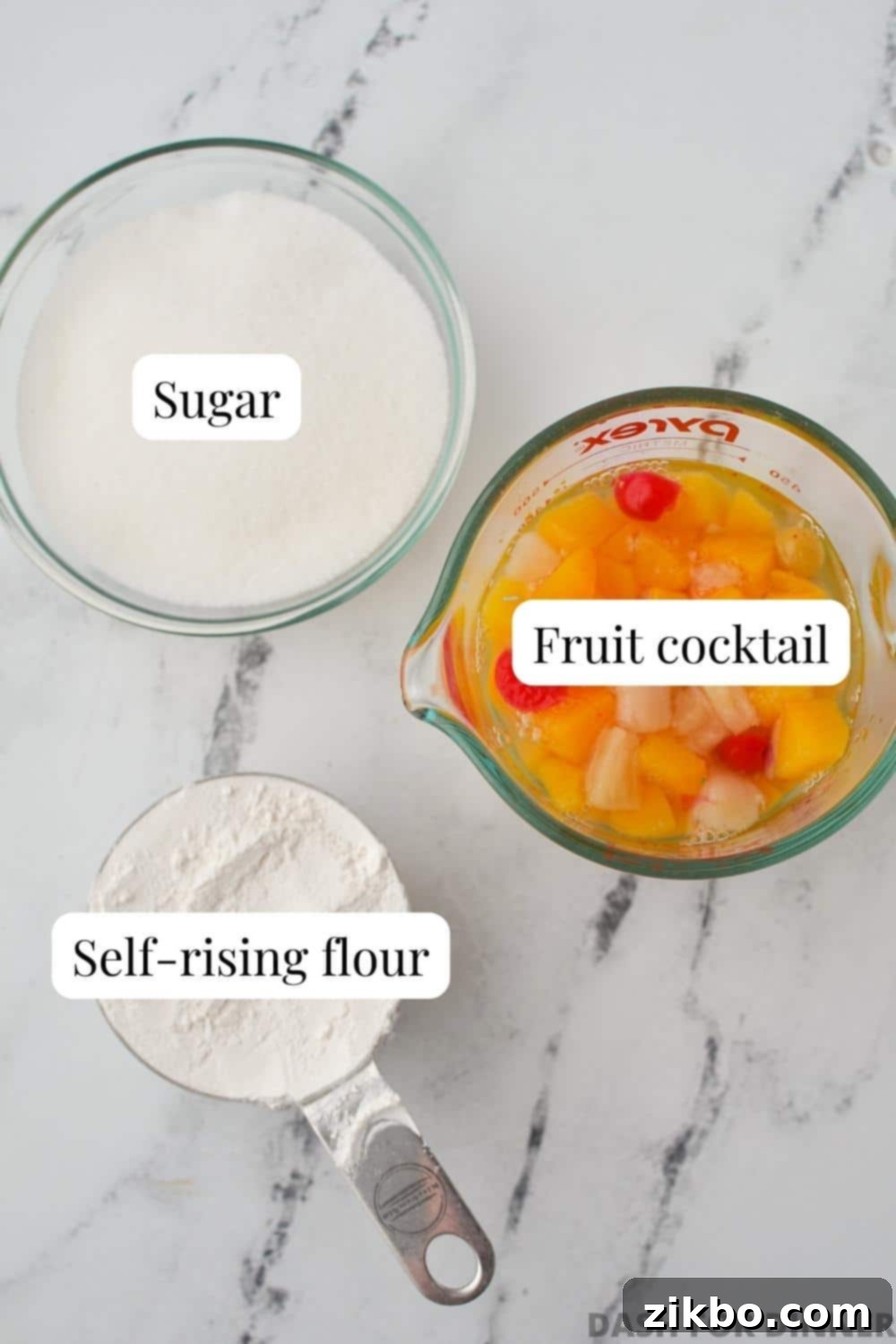 The three simple ingredients required to make Cuppa Cake: a can of fruit cocktail, a bag of self-rising flour, and a bowl of granulated sugar.
