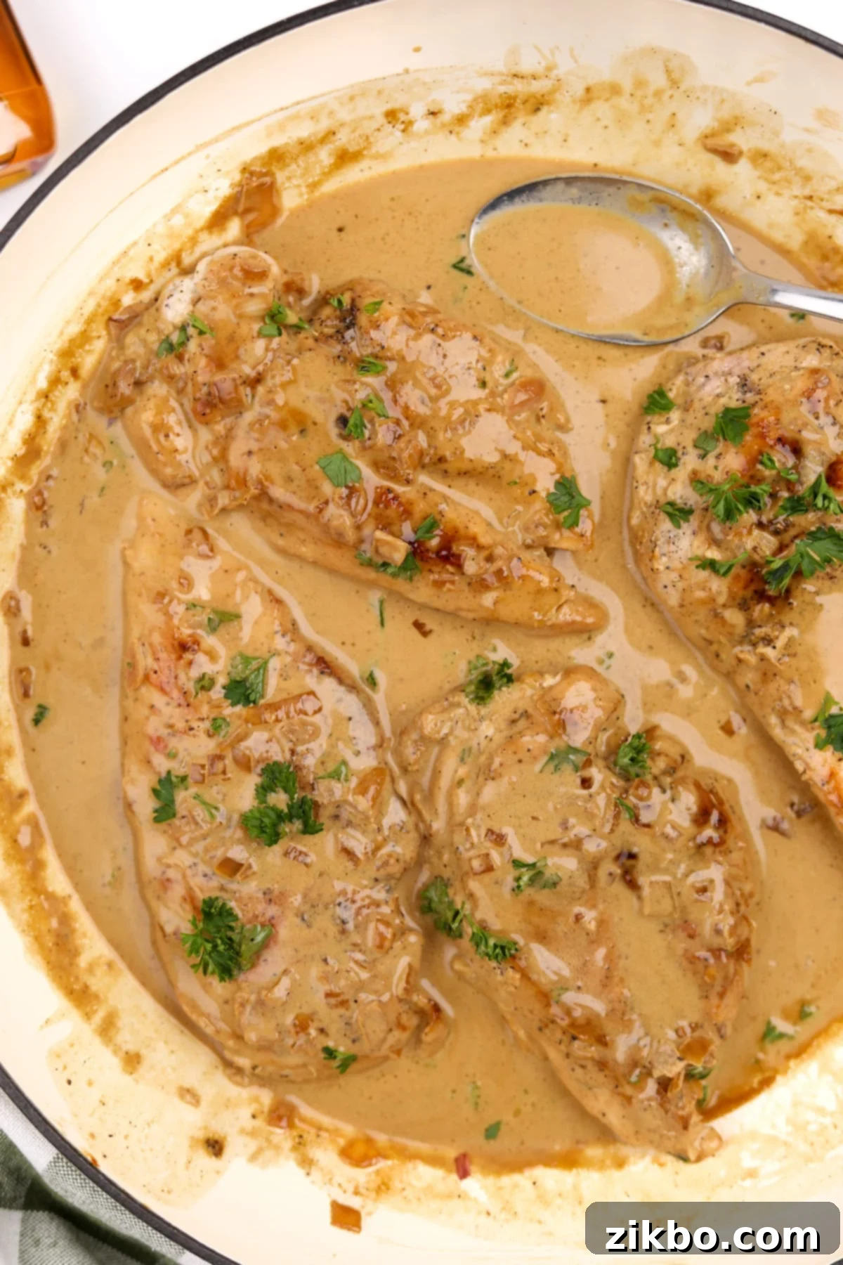 A skillet showcasing cooked chicken breasts covered in a generous amount of creamy Diane sauce, ready to be served.