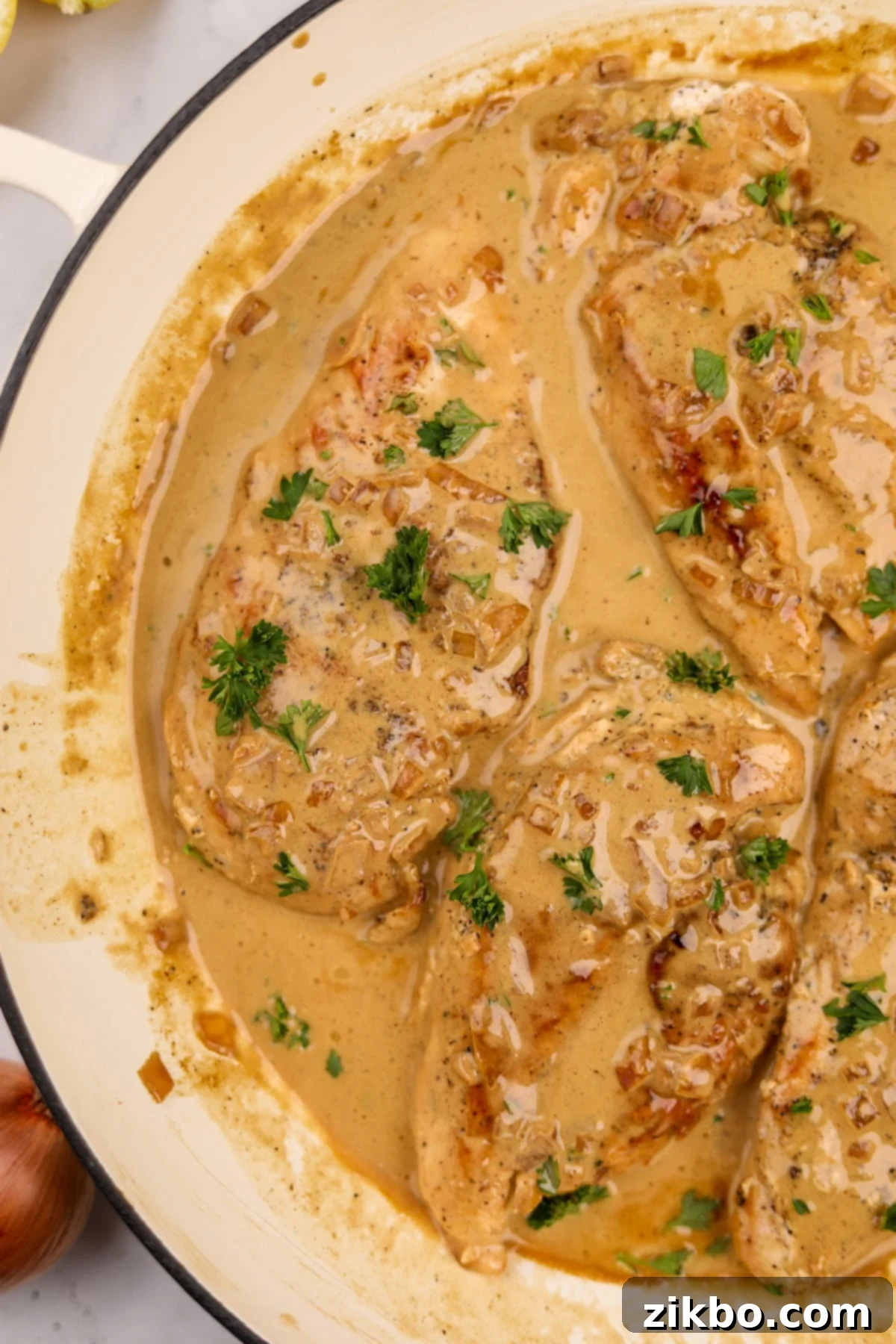 A beautifully presented coated cast iron skillet filled with creamy Chicken Diane, garnished with fresh parsley.