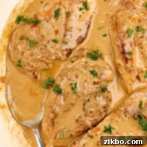 A spoon with creamy sauce in a skillet of chicken cutlets.