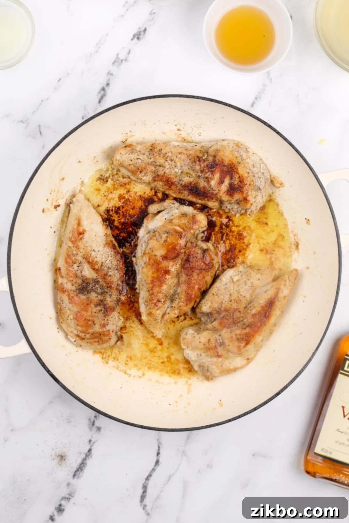 Perfectly browned chicken breasts resting in a skillet after being seared on both sides, showcasing a delicious golden crust.
