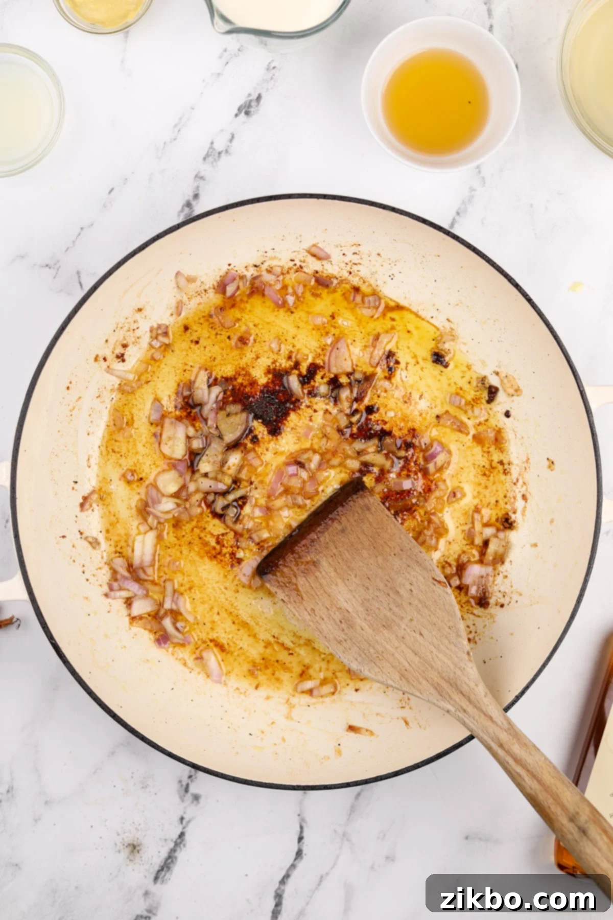 Minced shallots gently cooking in a skillet with the remaining butter and oil, becoming translucent and fragrant.