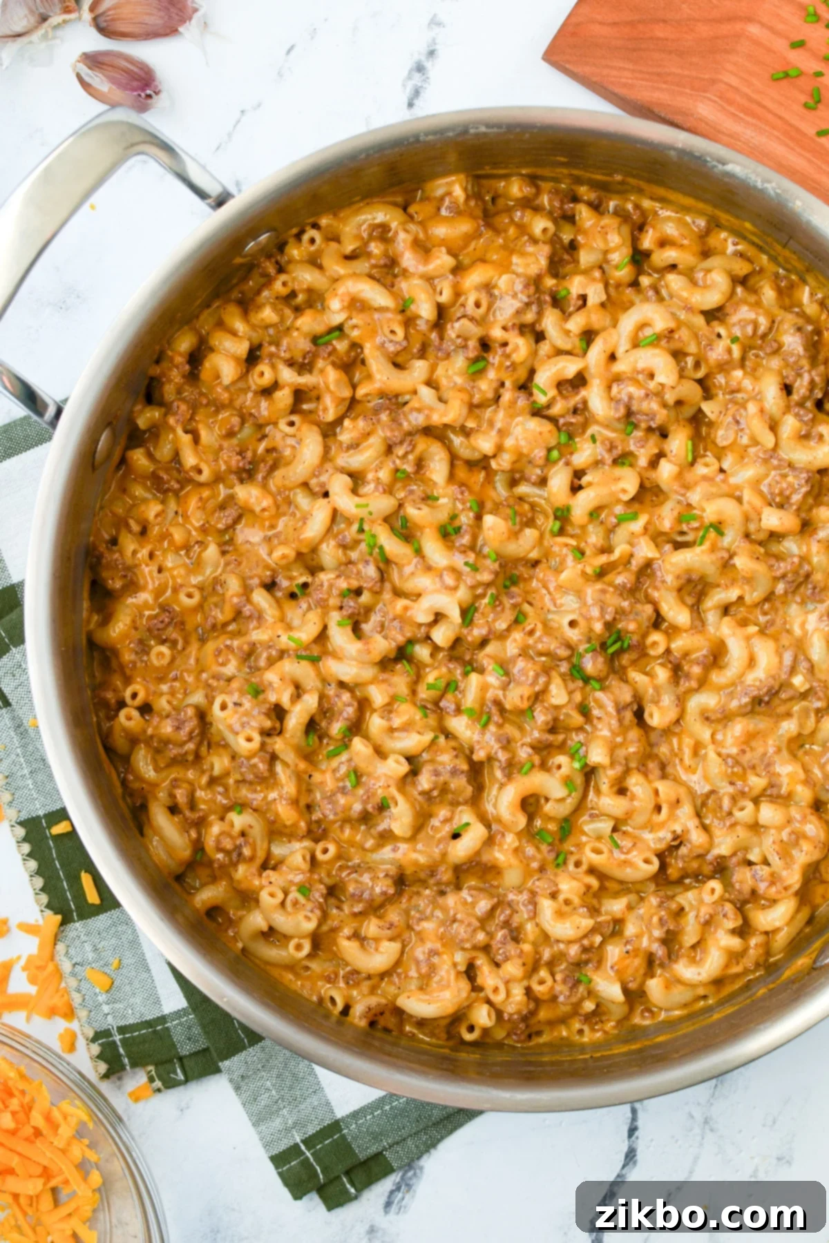A skillet with a steaming, creamy ground beef and macaroni mixture, ready to be served.