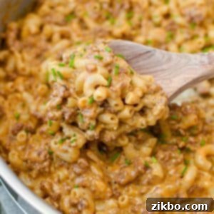 A wooden spoon scooping out a portion of hamburger helper, showing its creamy texture.