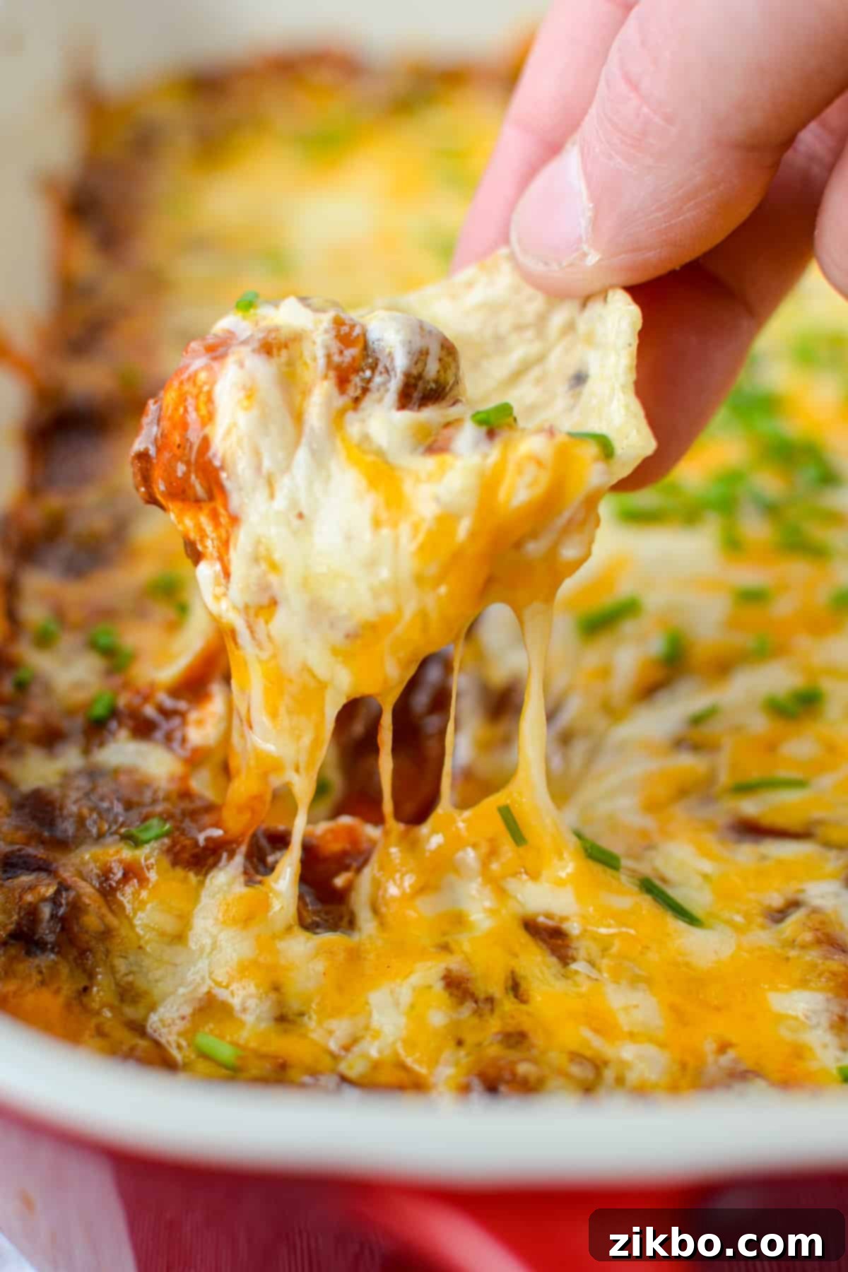 Easy Chili Cheese Dip 2 Dipping a scoop tortilla chip into a cheesy chili cheese dip.