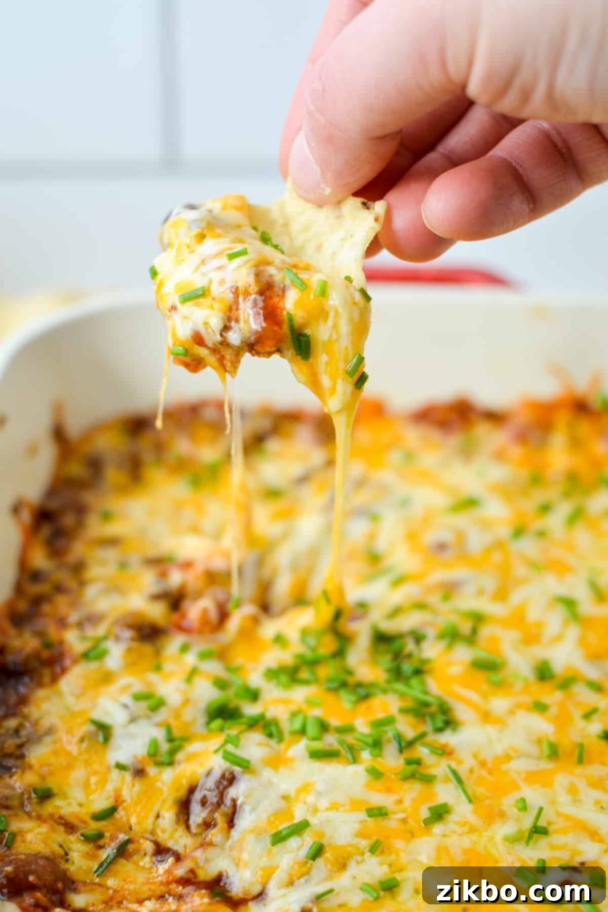 Easy Chili Cheese Dip 7 Dipping a tortilla chip into a hearty, cheesy chili cheese dip.