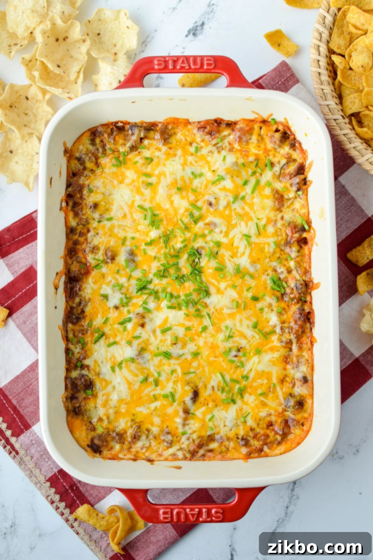 Easy Chili Cheese Dip 9 A baking dish filled with chili cheese dip, with corn chips and tortilla chips spread around for serving.