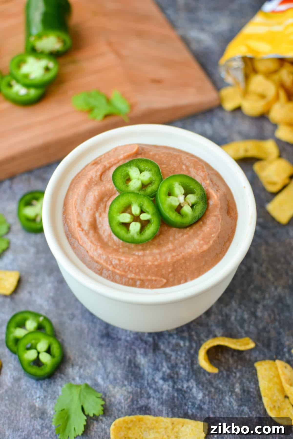 Ultimate Homemade Fritos Bean Dip 2 A small bowl of bean dip garnished with jalapeños, ready for serving.