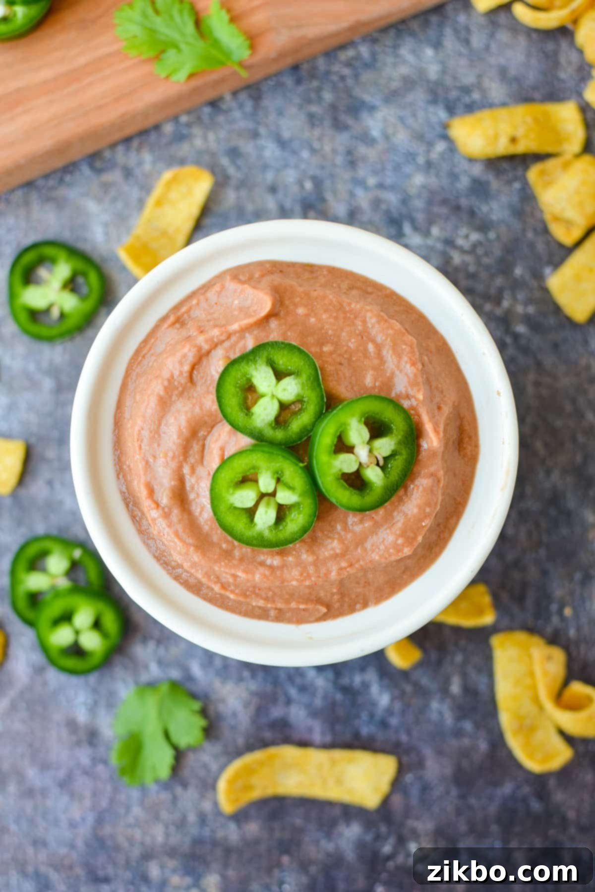 Ultimate Homemade Fritos Bean Dip 6 A beautifully presented bowl of creamy bean dip, garnished with fresh jalapeno slices on top, ready for dipping.
