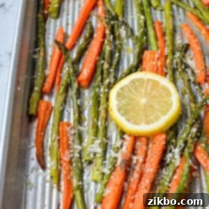 A sheet pan with roasted carrots and asparagus, garnished with lemon slices, a perfect healthy side dish.