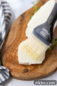 Brushing oil on a slice of halloumi cheese before air frying.