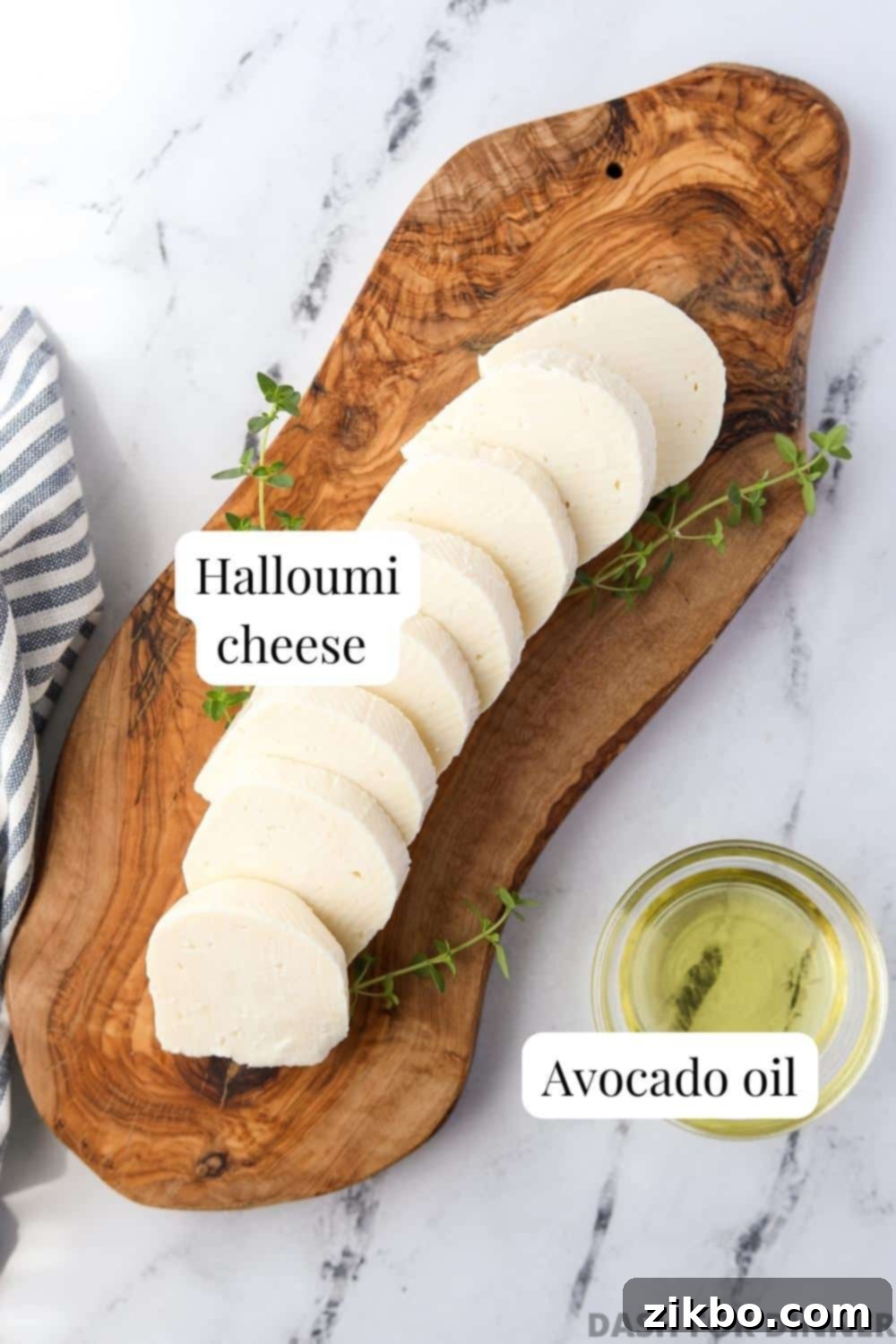A wooden board with sliced halloumi and a small bowl of avocado oil, ready for air frying.
