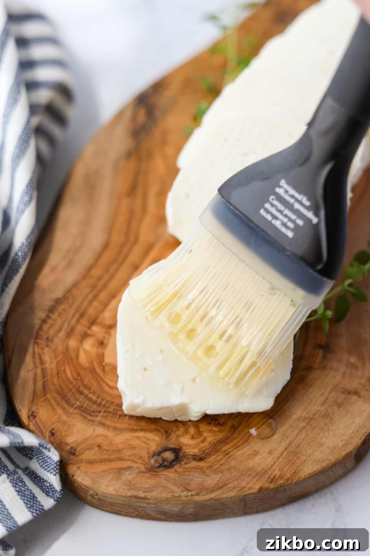 Brushing a thin layer of oil on a slice of halloumi cheese before air frying.