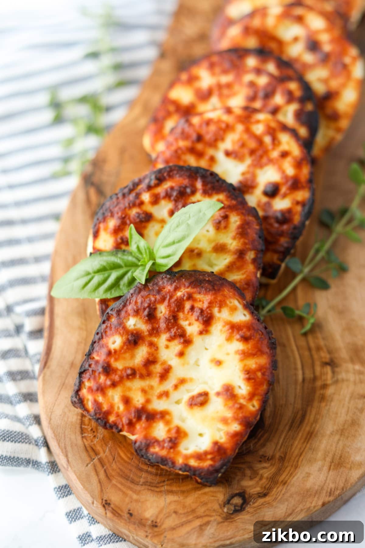 Fried halloumi cheese on a wooden board, garnished with fresh basil leaves.