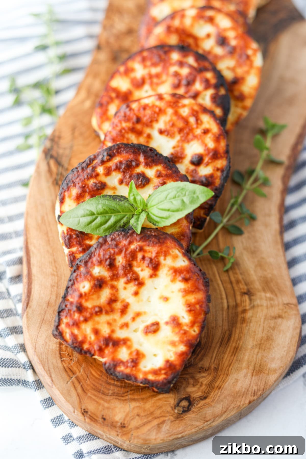 Garnishing a slice of golden-brown fried halloumi cheese with fresh basil leaves.