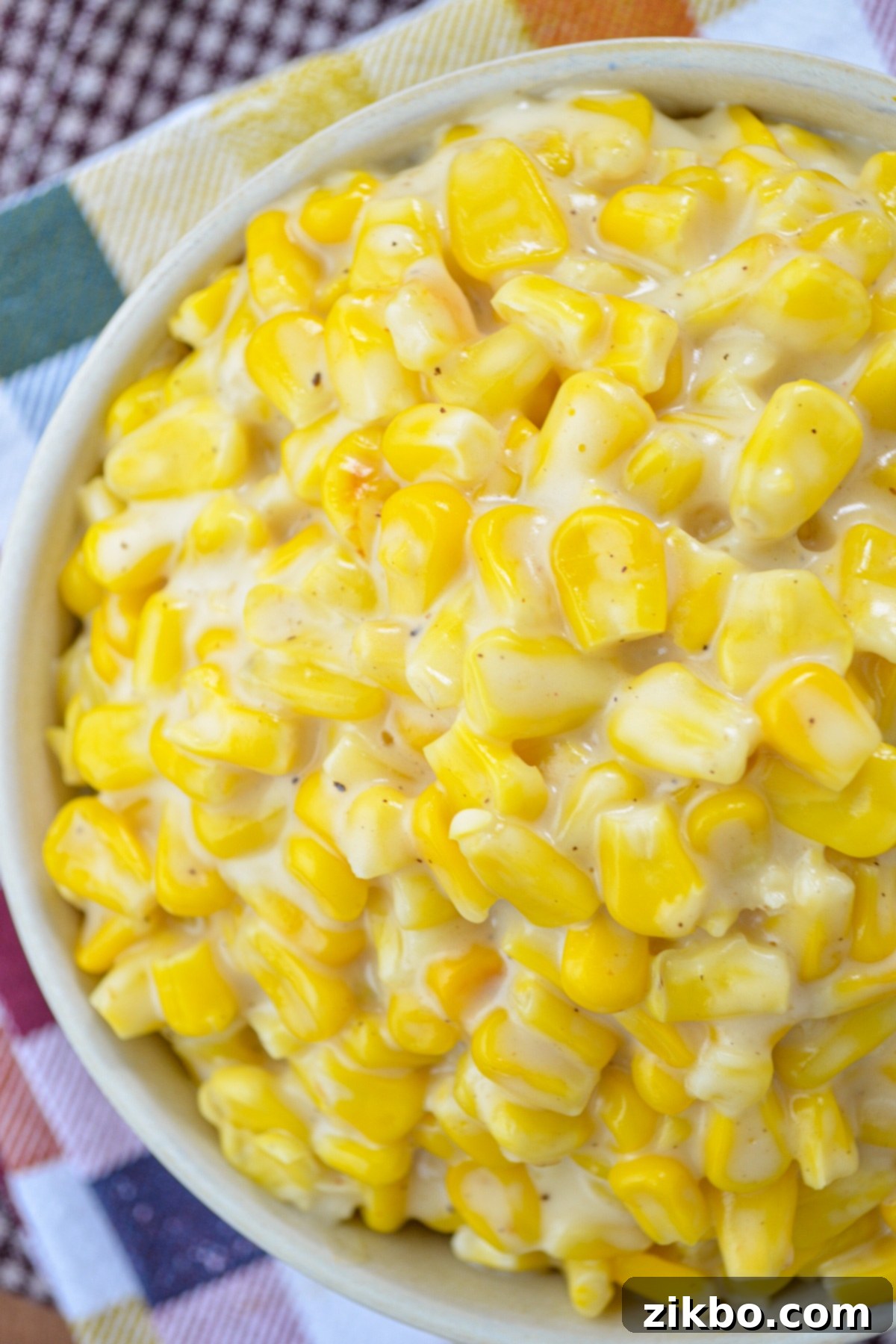 A close up of a bowl of rich, creamy homemade Instant Pot creamed corn, garnished for a holiday meal.