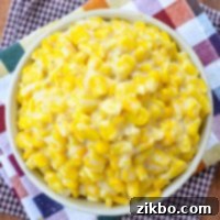 A bowl of creamed corn, resting on two fall inspired cloth napkins.