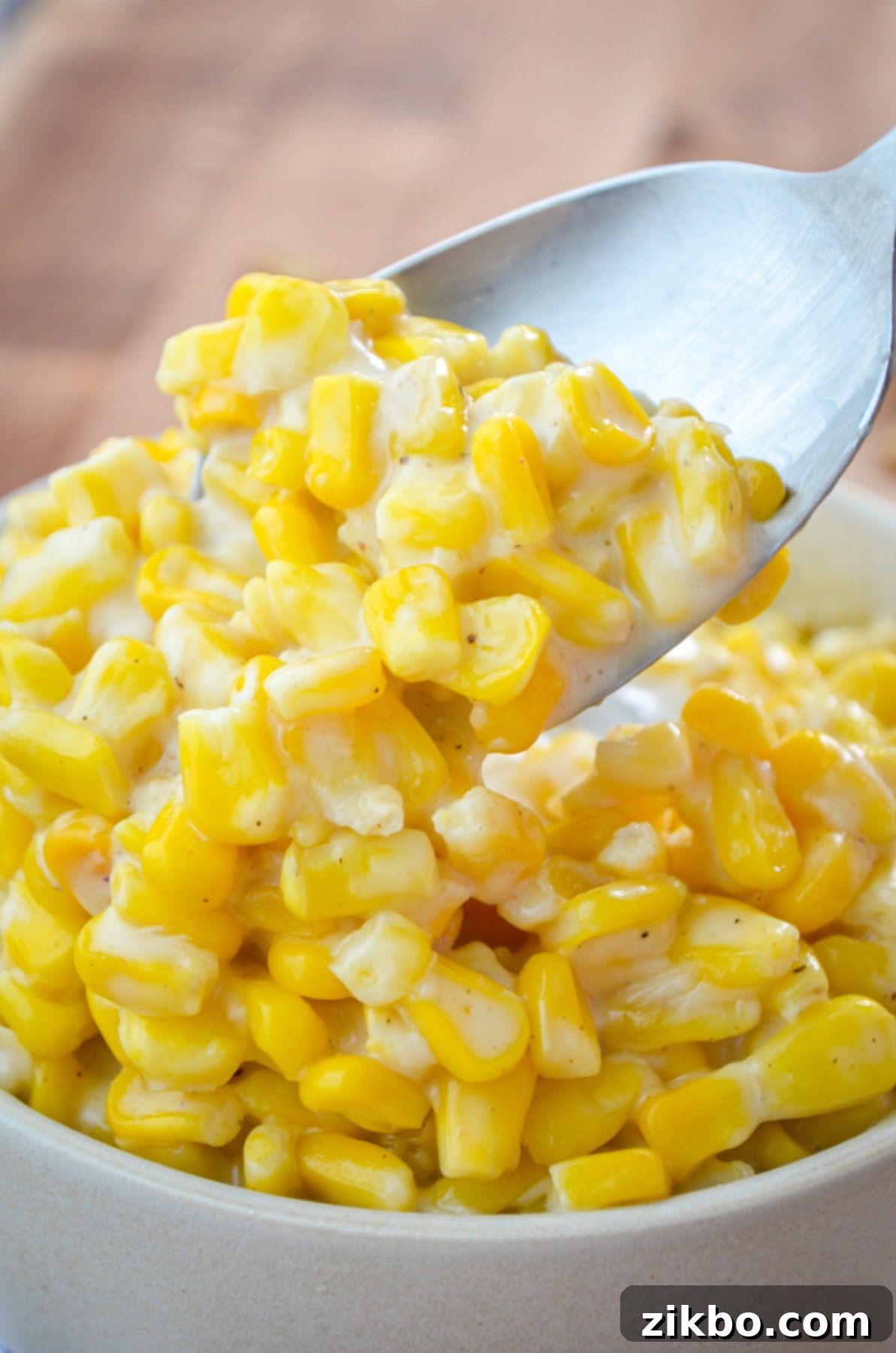 A bowl of rich Instant Pot creamed corn, with a large serving spoon scooping out a portion for a holiday plate.