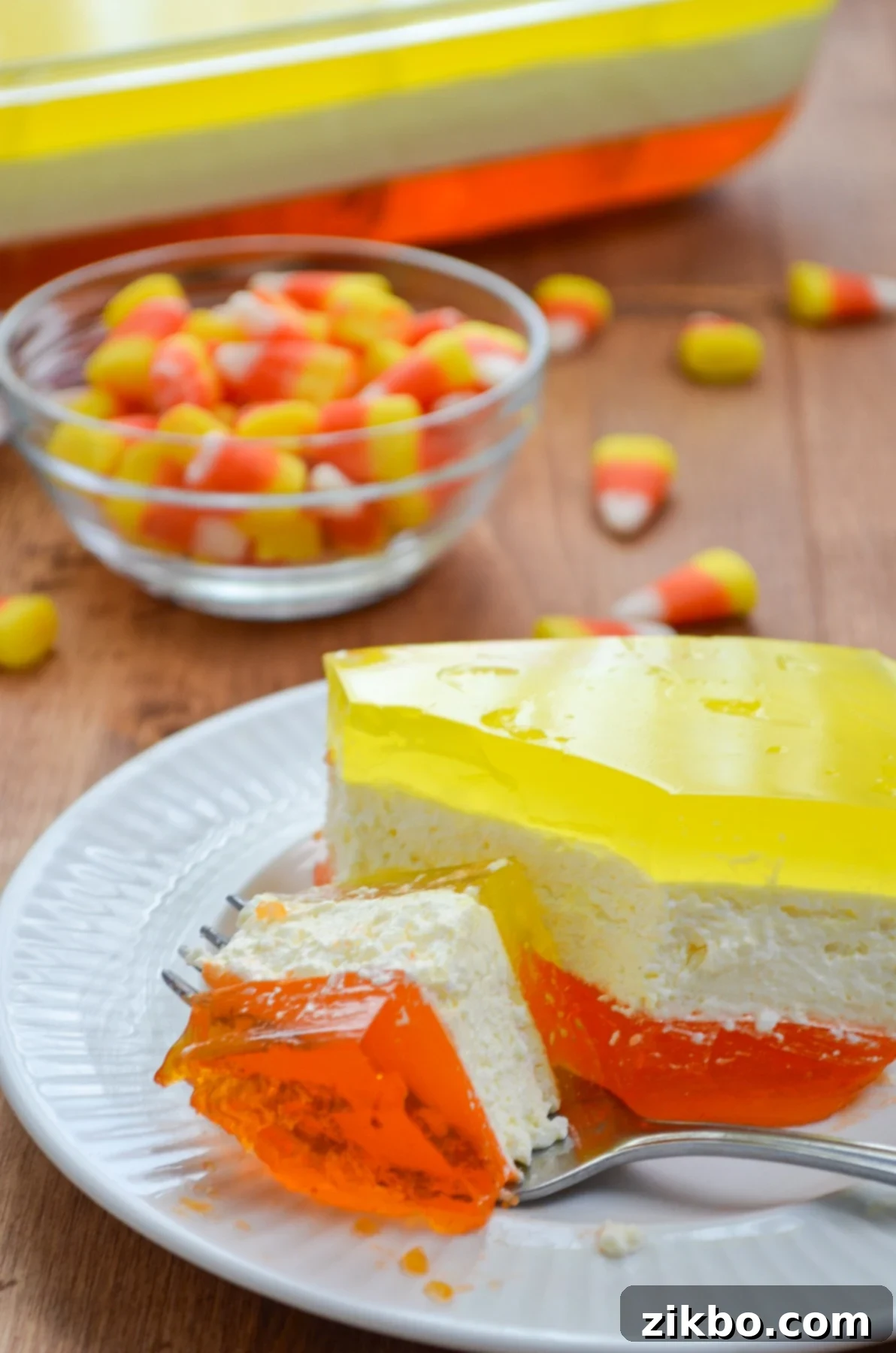 A perfectly sliced piece of layered Halloween Jell-O showing its distinct orange, white, and yellow layers.