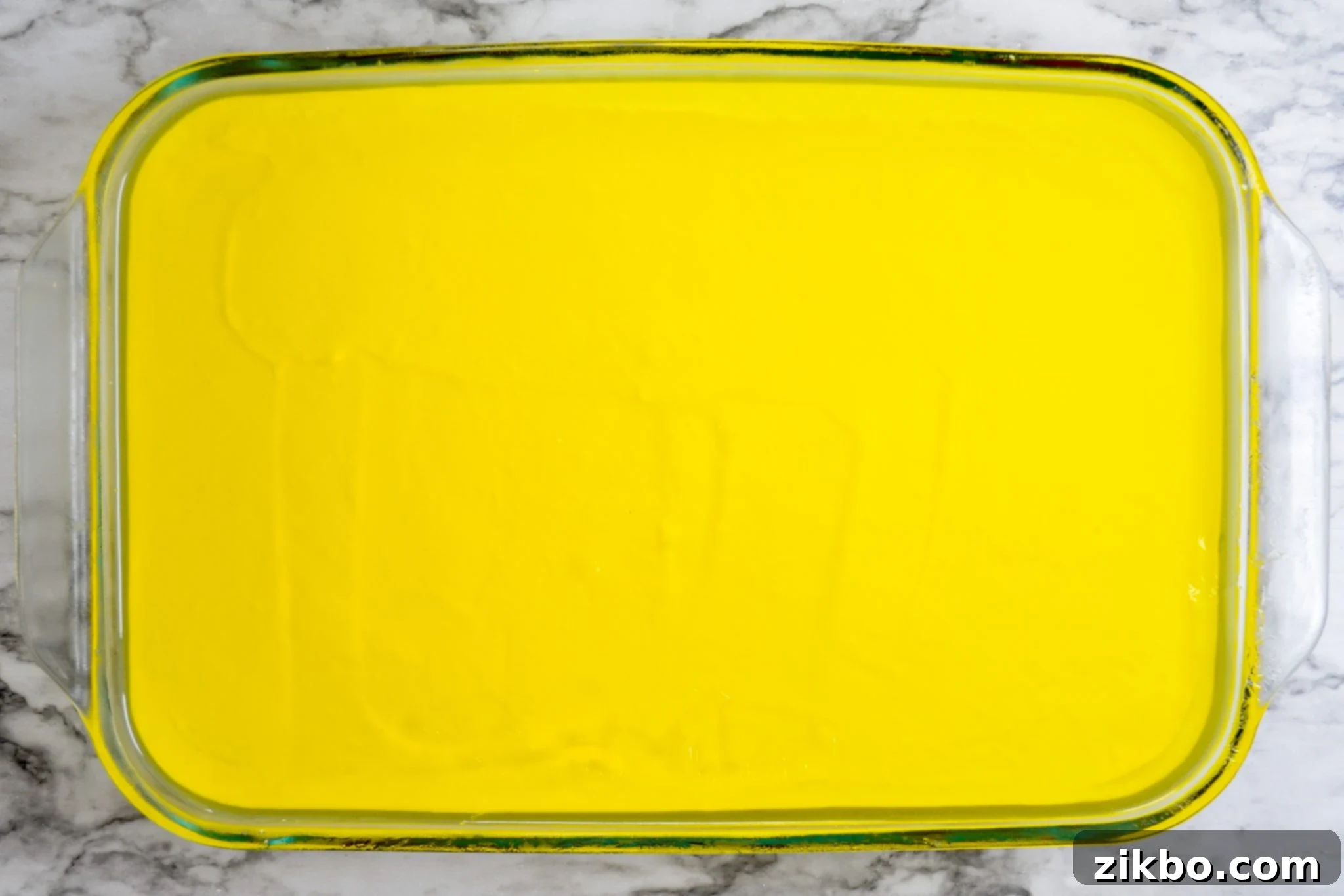 The final, lemon Jell-O layer being gently poured over the creamy white layer for Halloween Jell-O.