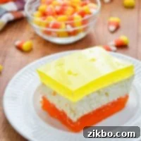 A Jell-O dessert with three distinct layers, using Halloween-inspired colors of orange, white, and yellow.