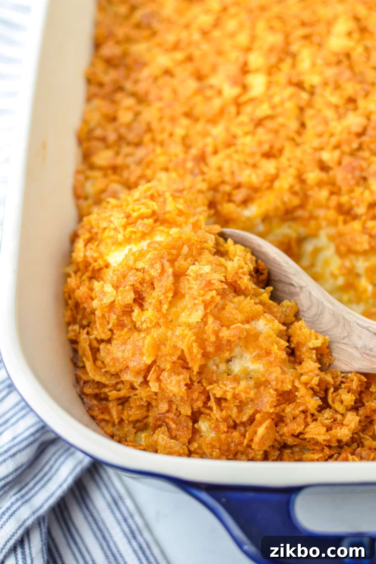 Scooping out hash brown casserole with a wooden spoon.