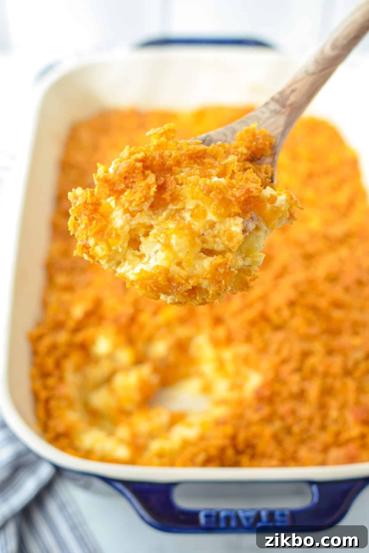 A wooden spoon taking a portion of party potatoes.