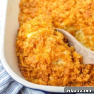 Scooping a small amount of hash brown casserole with a wooden spoon.