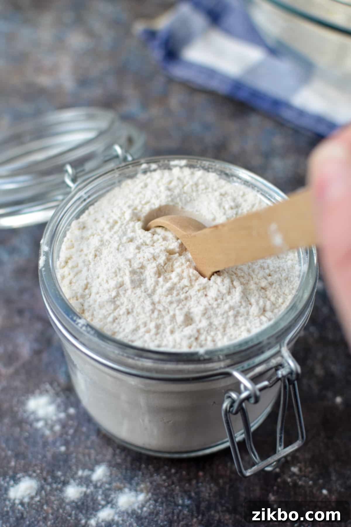 A small jar of finished homemade self-rising flour with a wooden spoon.
