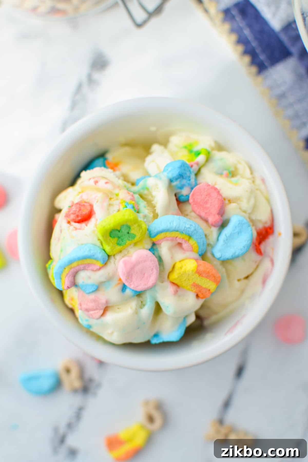 An overhead view of a small bowl of homemade lucky charms ice cream, garnished with extra marshmallows.