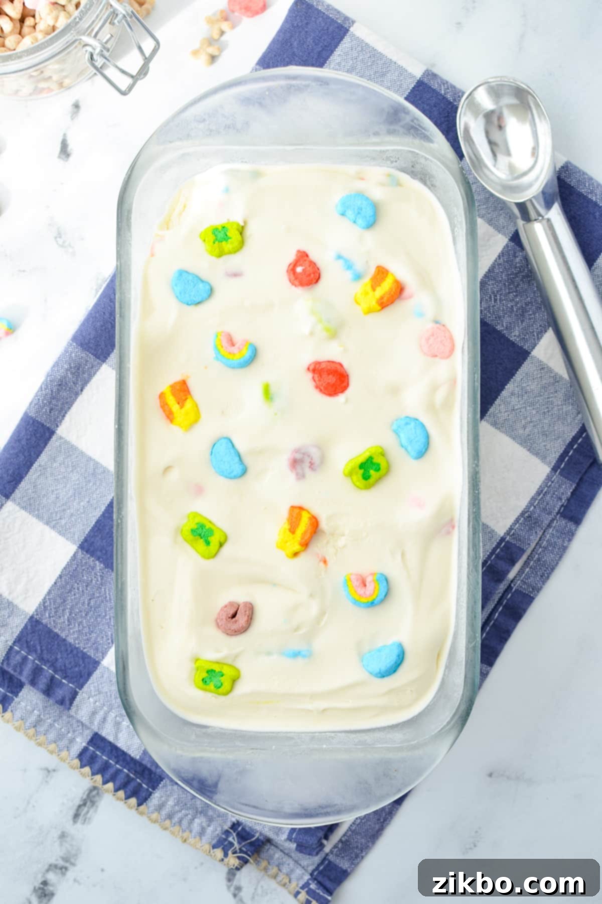 A loaf pan filled with vibrant Lucky Charms ice cream and dotted with colorful marshmallows.